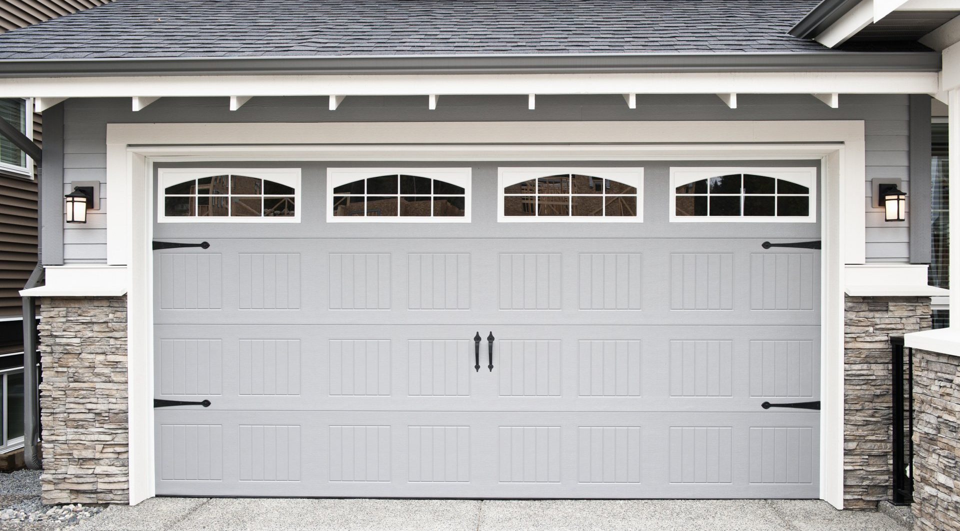 A garage door with small windows painted light grey by an exterior painting company