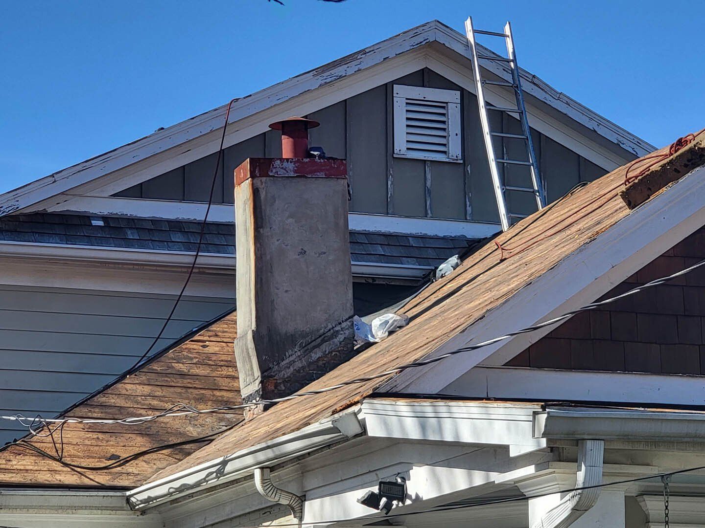 A house with a chimney and a ladder on the roof.