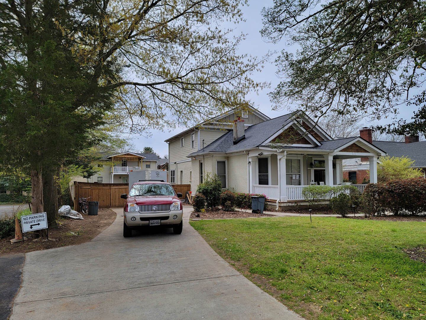 A car is driving down a driveway in front of a house.