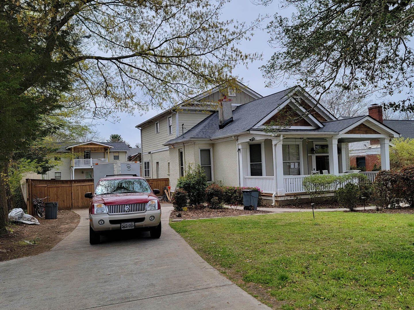 A car is parked in front of a house on a sunny day.