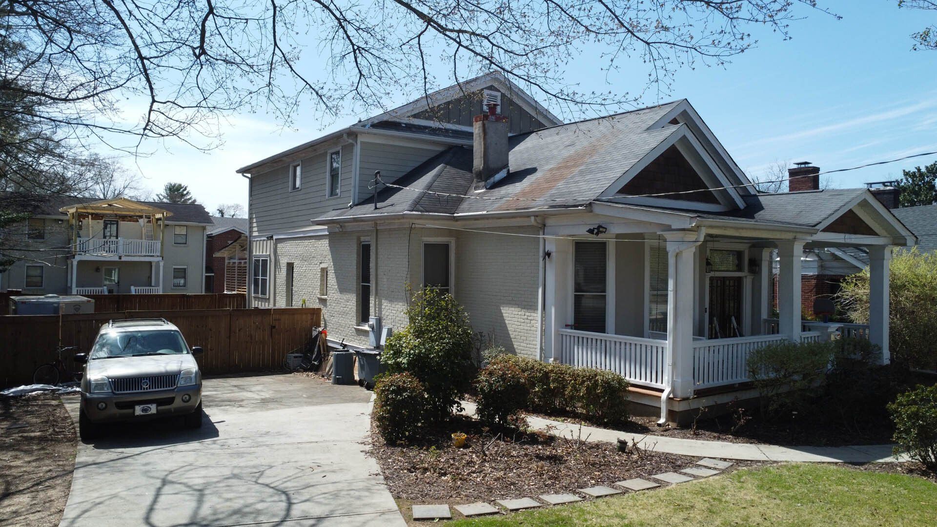 A white car is parked in front of a house