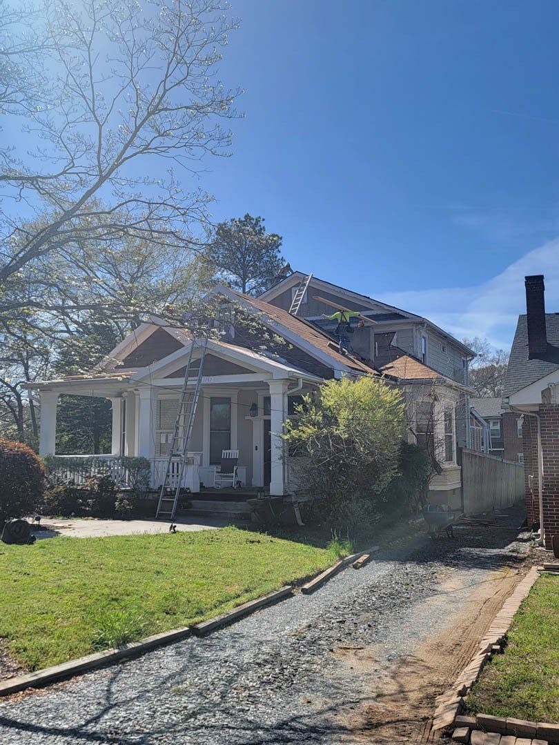 A white house with a brown roof is sitting on top of a lush green lawn.