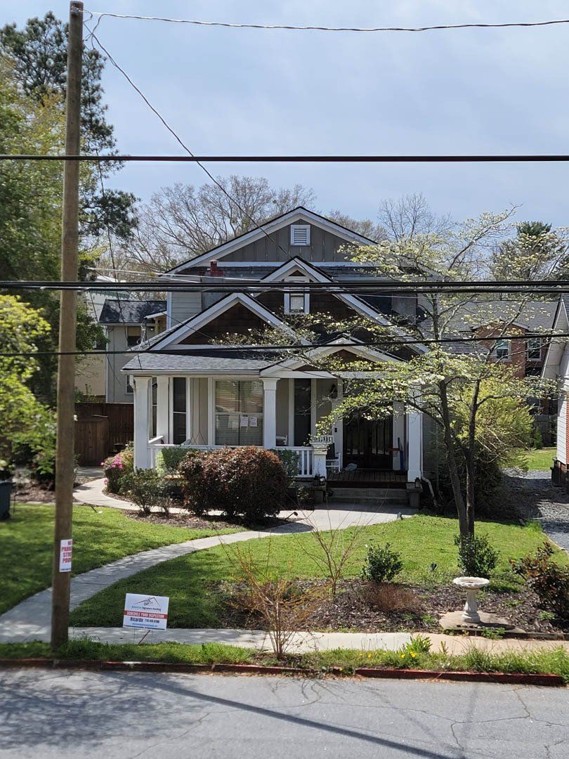 A house with a sign on the sidewalk in front of it.