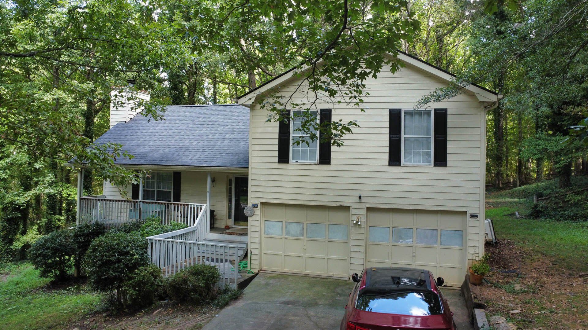 A white house with a red car parked in front of it.