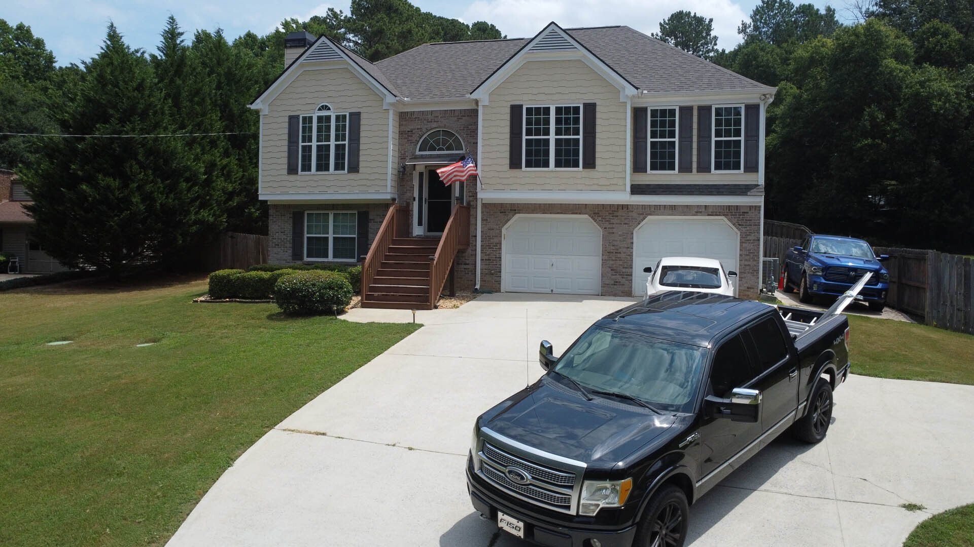 A black truck is parked in front of a large house.