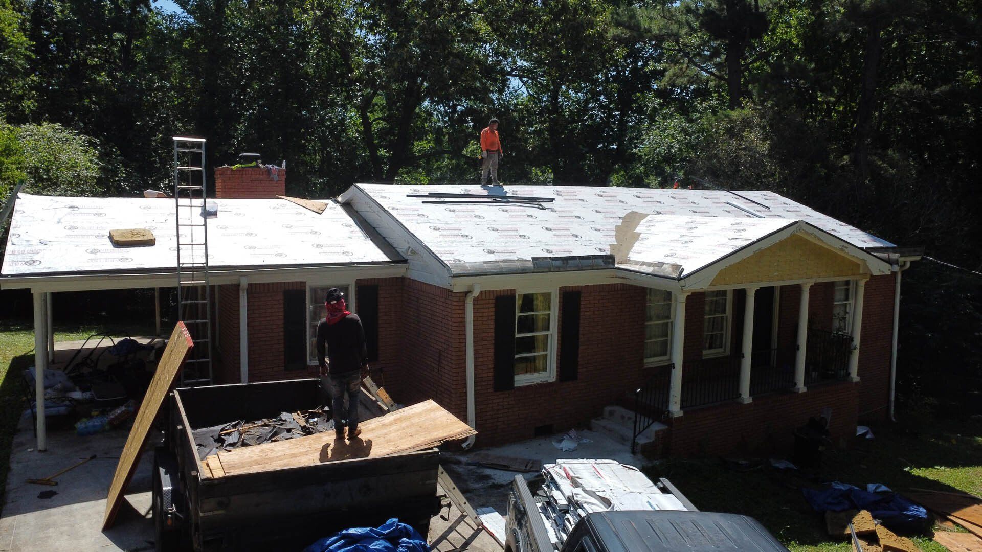 A man is standing on the roof of a brick house