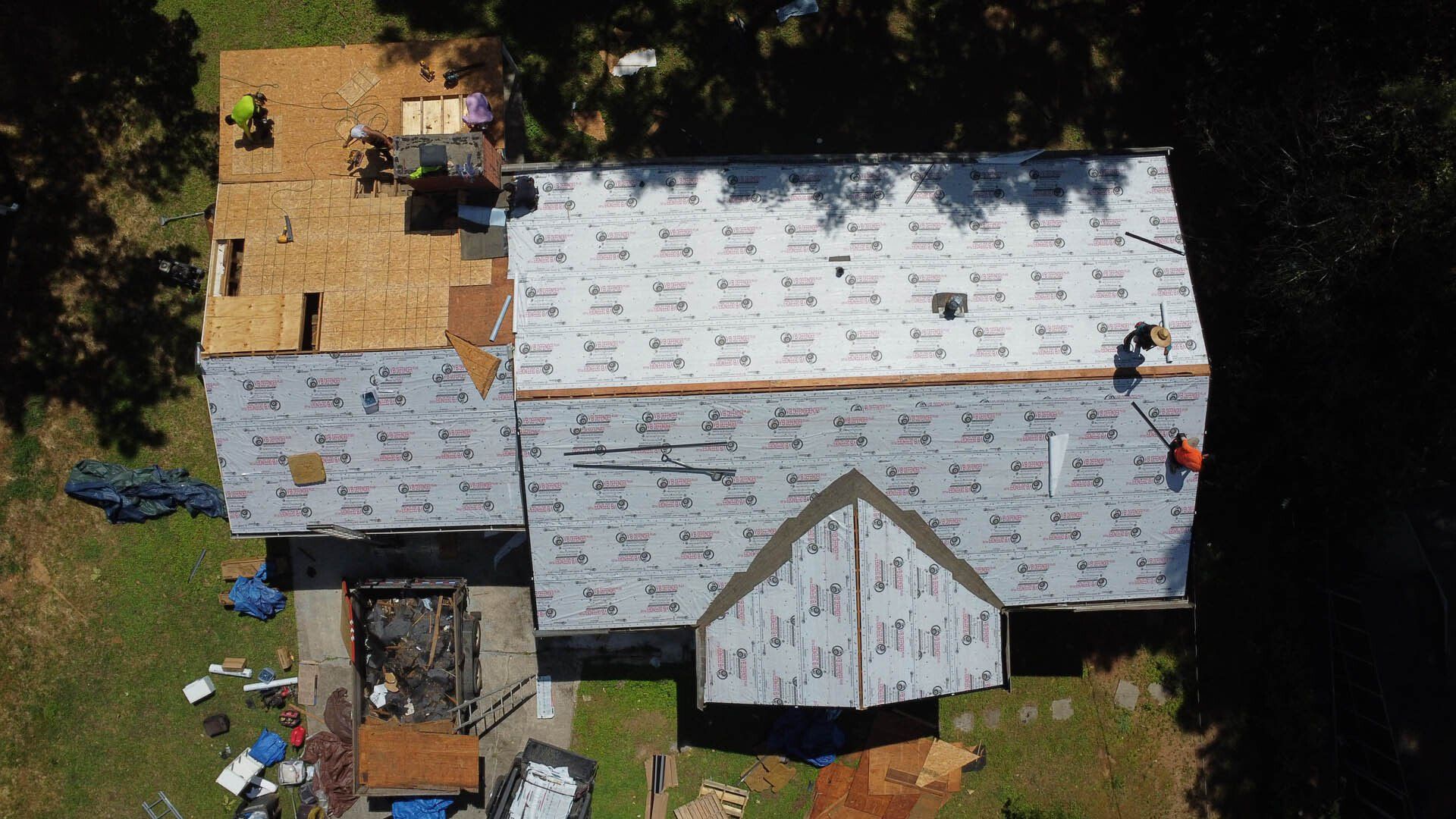 An aerial view of a house under construction with workers on the roof.