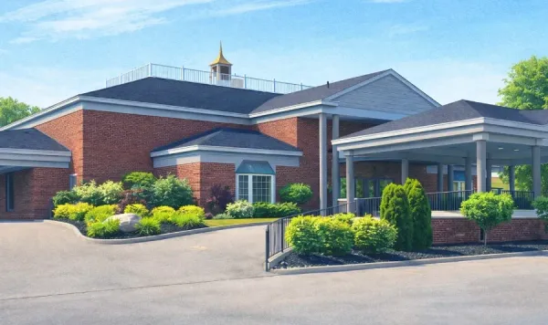 A light-colored, single-story building with a dark shingled roof, a covered entrance, and an American flag outside.