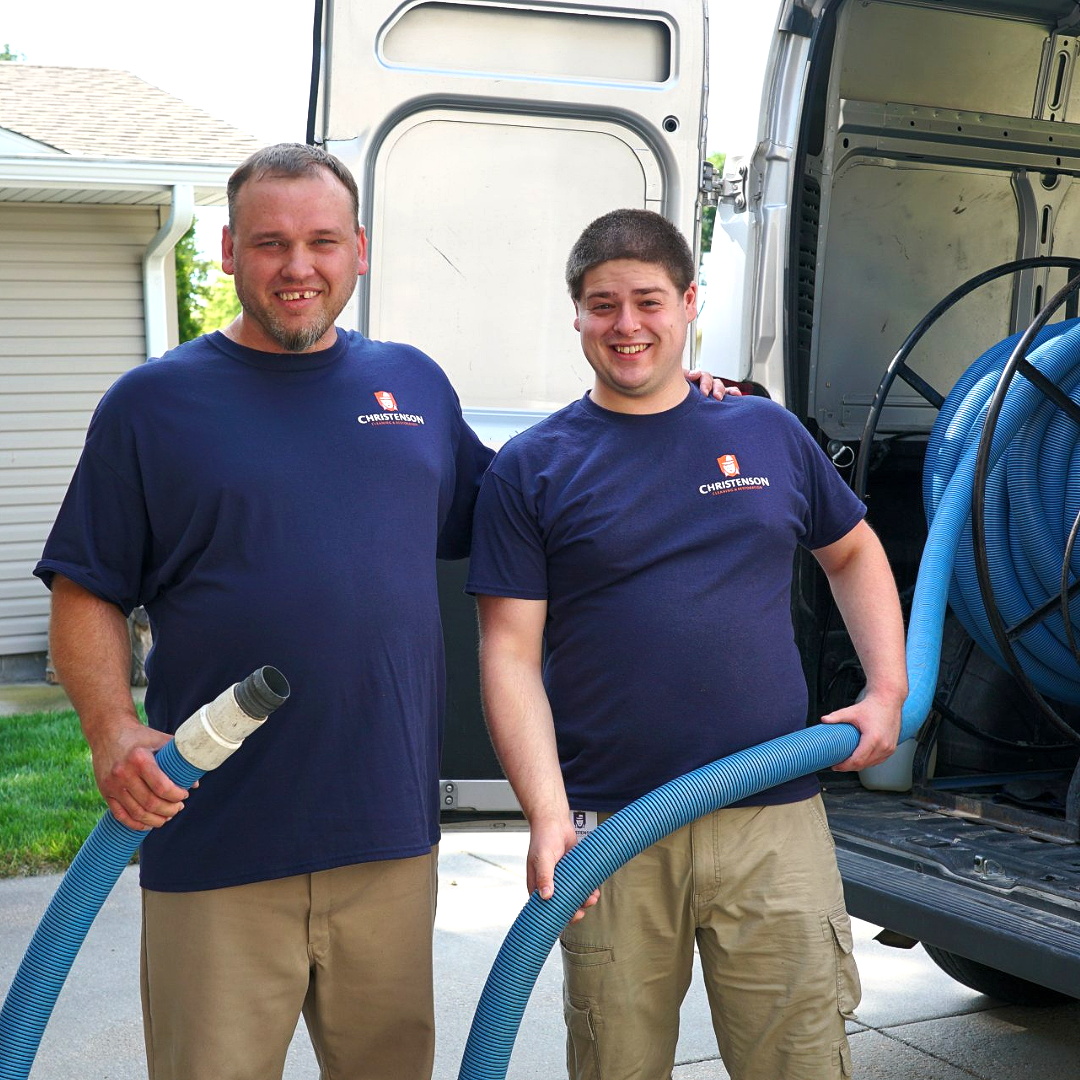 Two men standing next to each other holding blue hoses