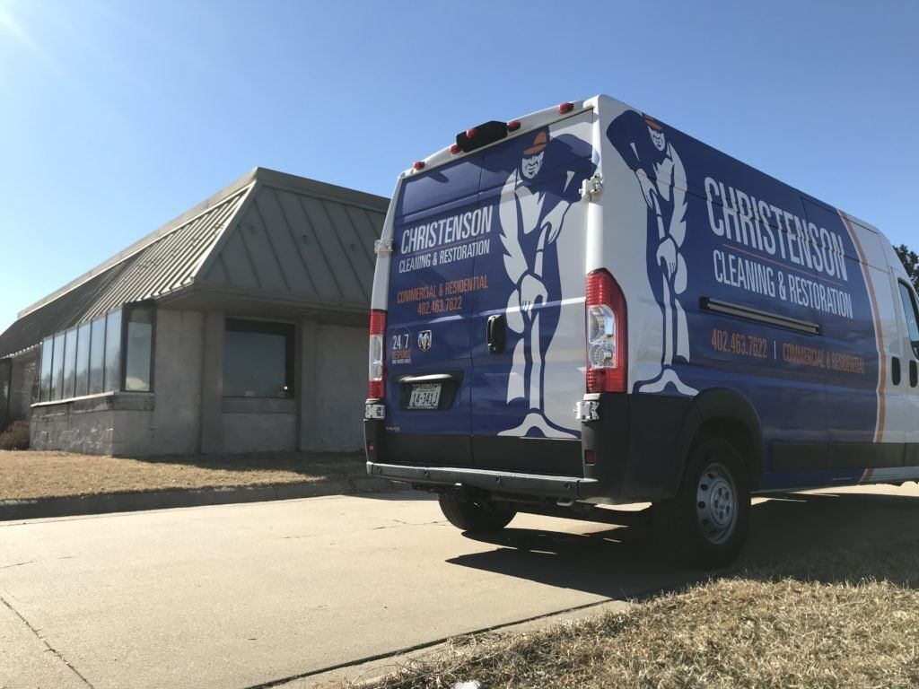 A blue and white van is parked in front of a building.