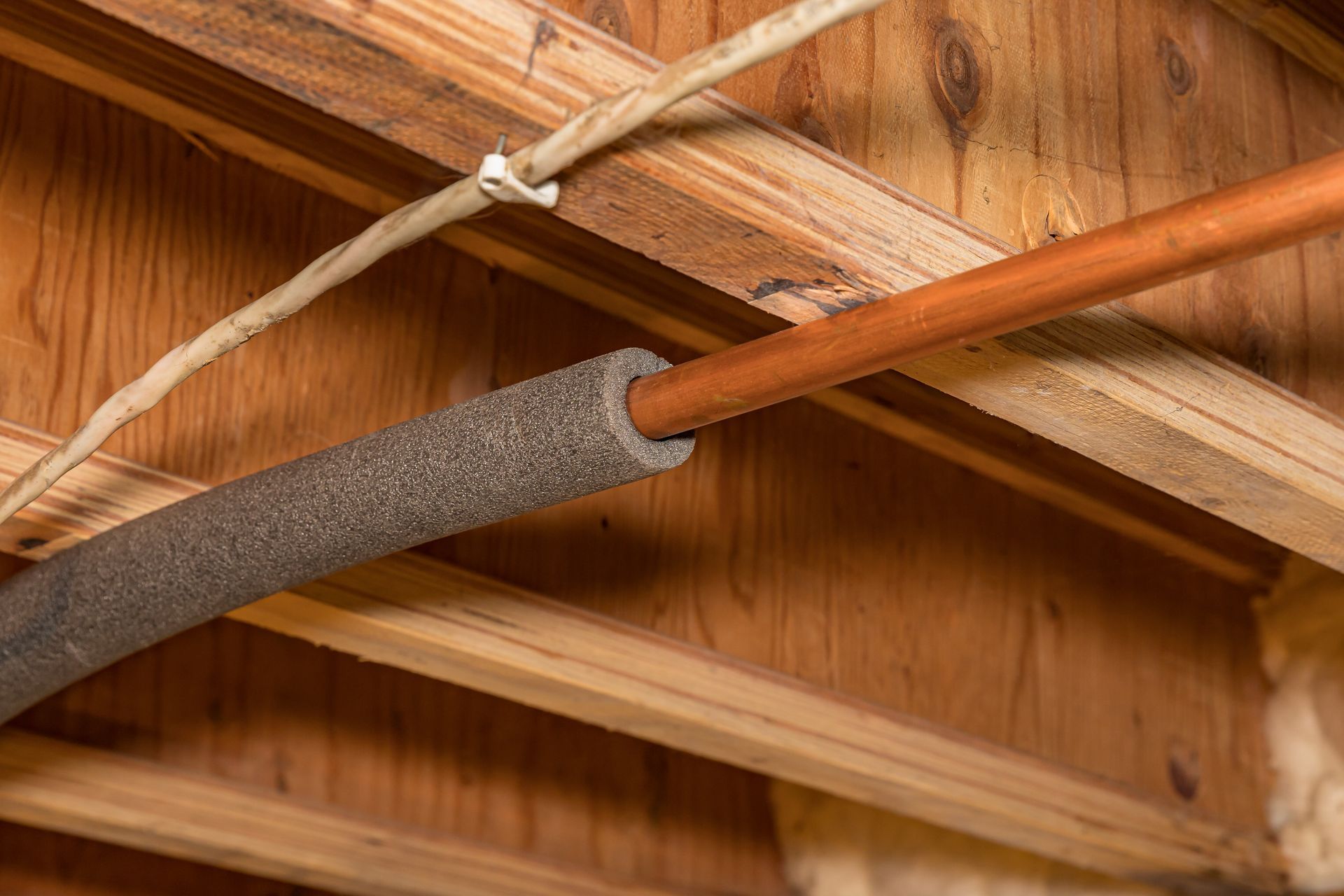 A close up of a copper pipe in a wooden structure.