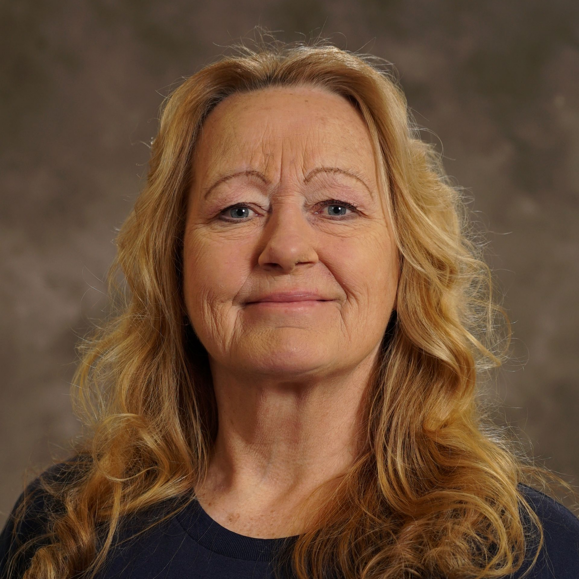 A woman in a purple shirt is smiling for the camera.