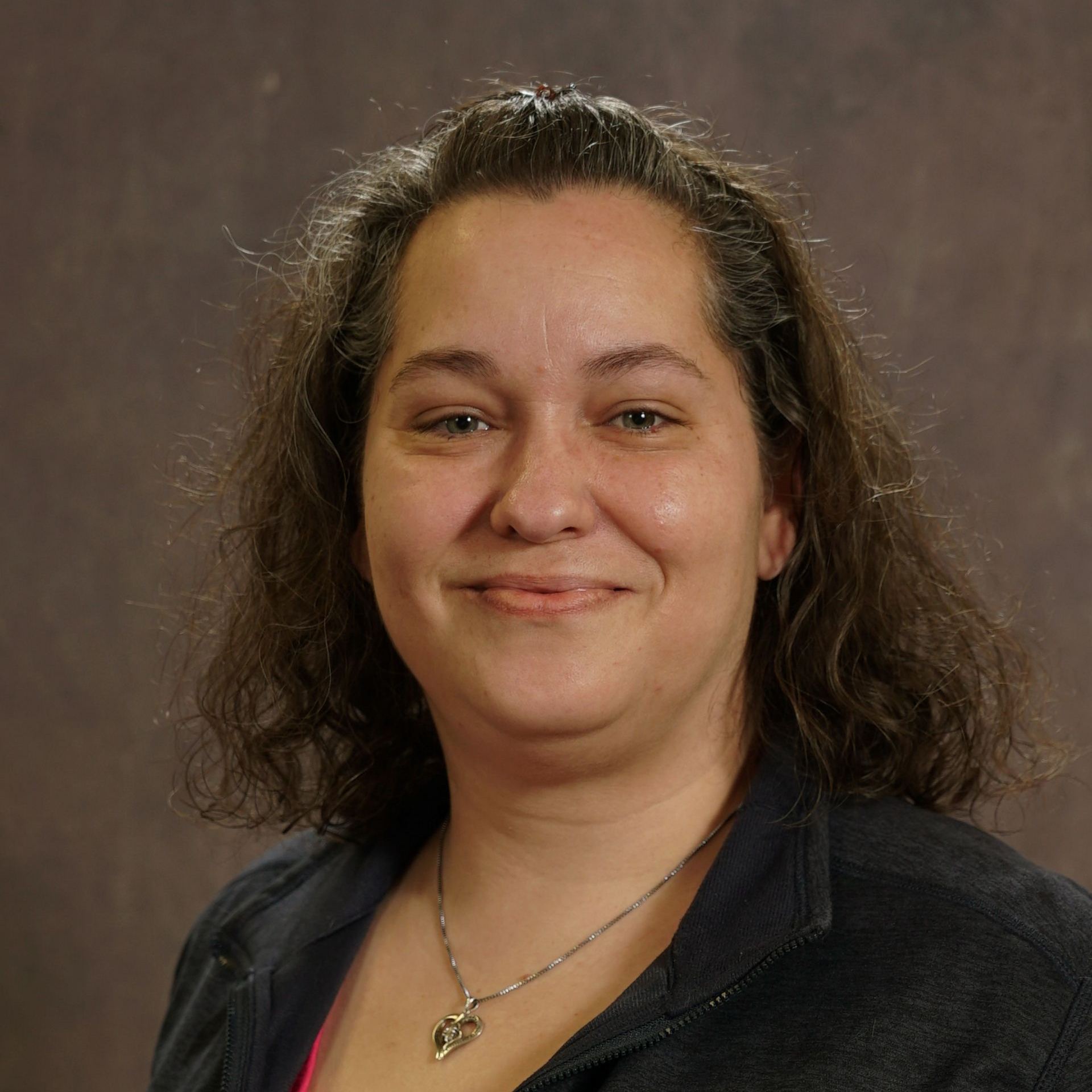 A woman with curly hair is smiling and wearing a black shirt