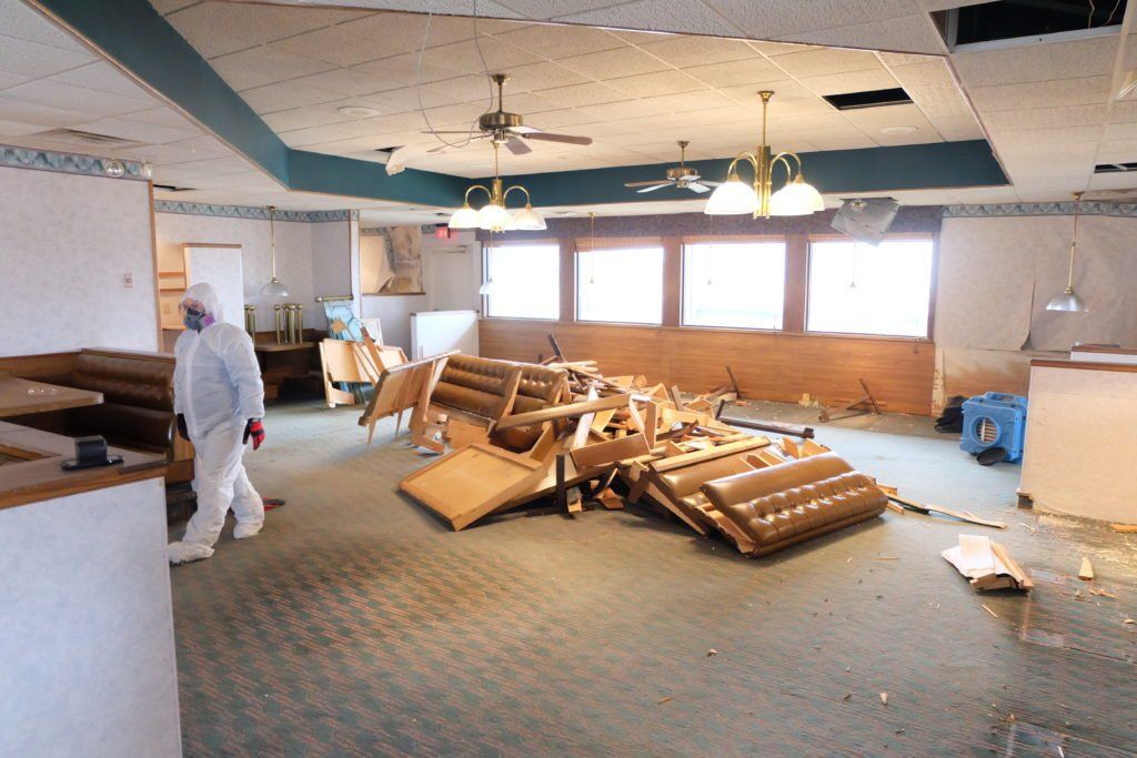 A man in a white suit is walking through an empty room
