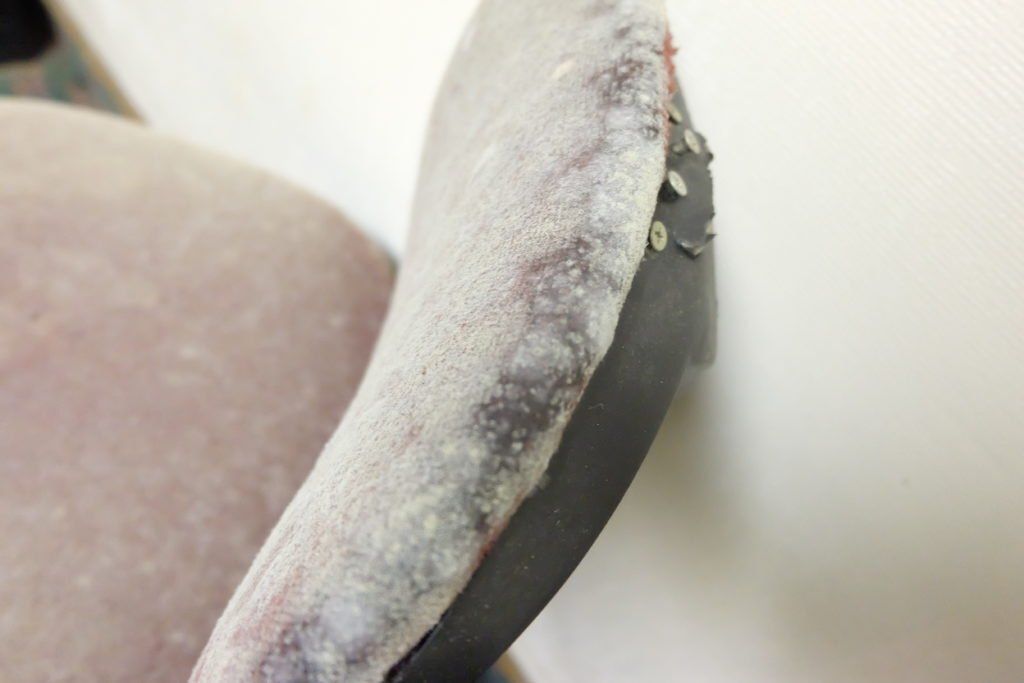 A close up of a chair arm rest with a white cloth on it.