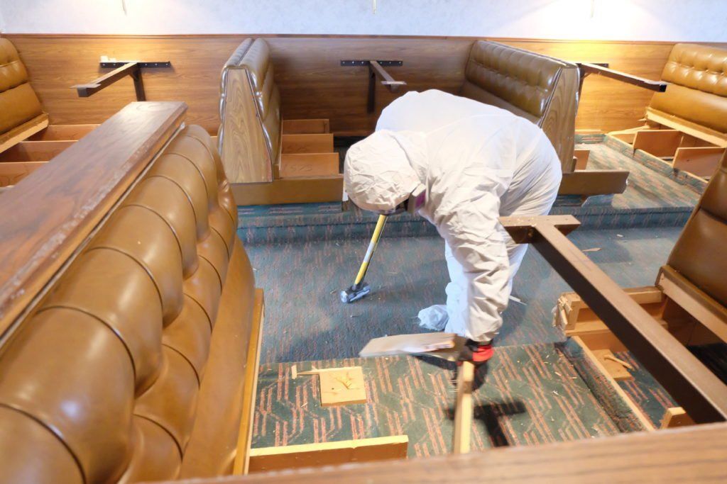 A man in a white suit is cleaning the floor of a restaurant
