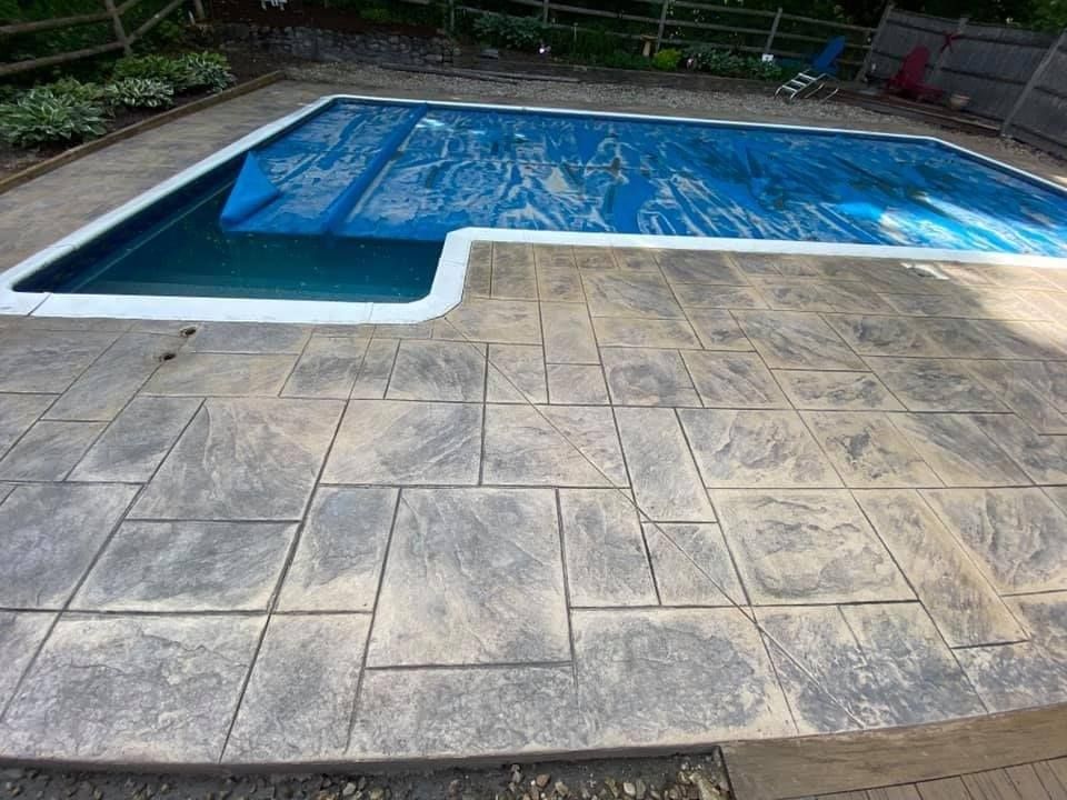 A swimming pool with a blue cover on it is surrounded by a concrete patio.