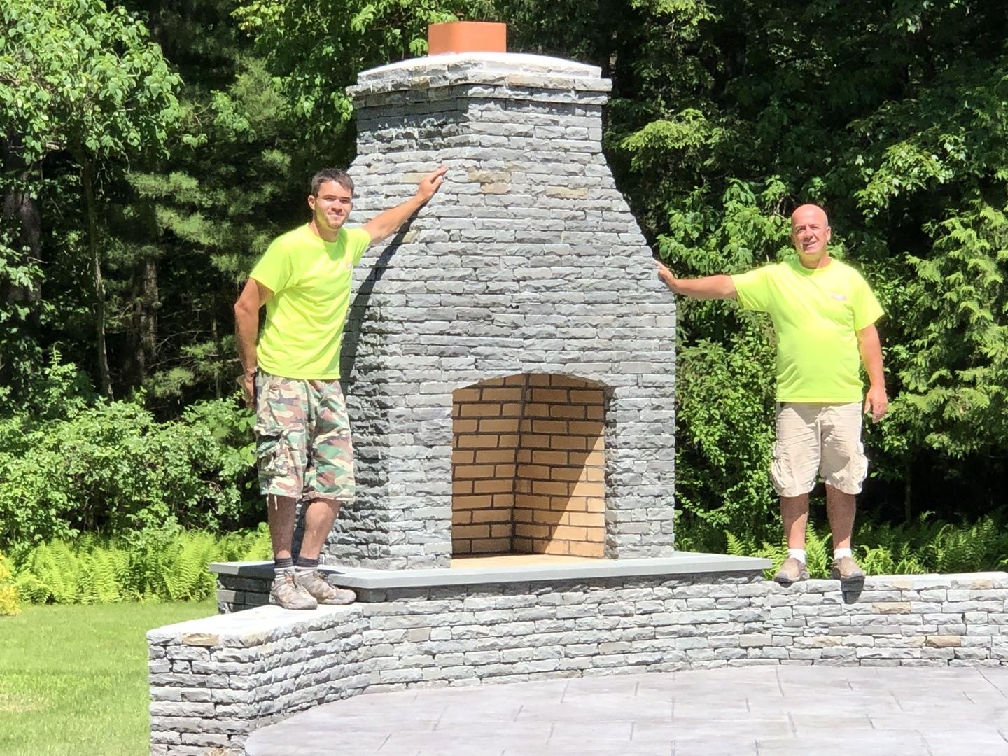 Two men standing in front of a brick fireplace