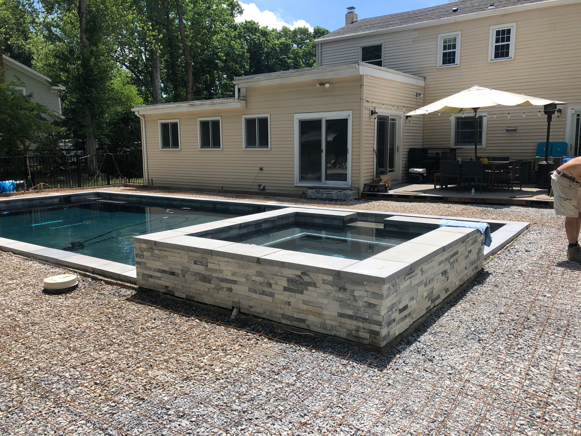 A man is standing in front of a large swimming pool.