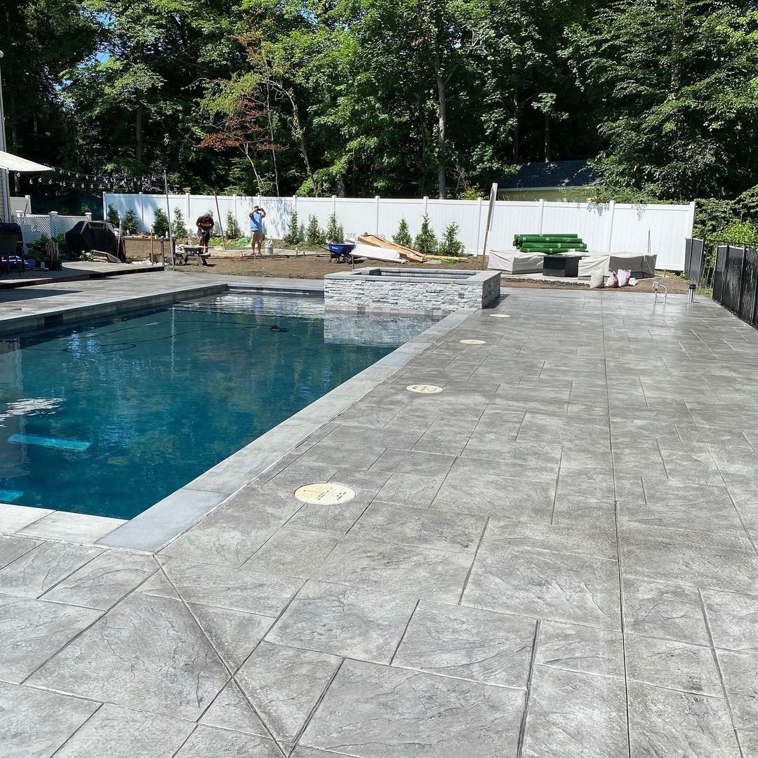 A large swimming pool is surrounded by a concrete patio.