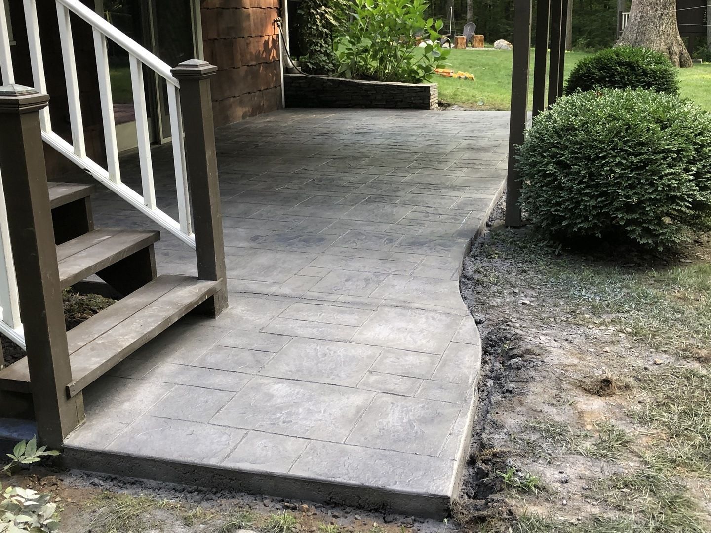 A concrete walkway leading to a porch with stairs.