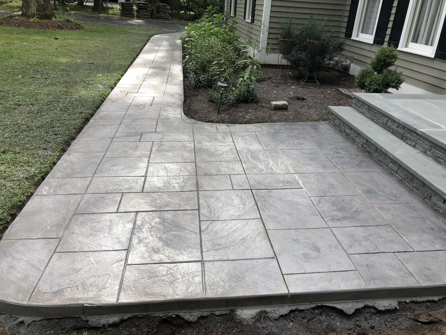 A concrete walkway with steps leading to a house.