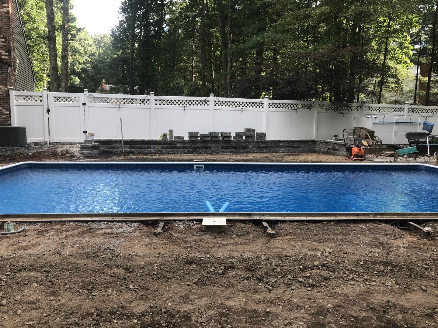 A large swimming pool is being built in a backyard.
