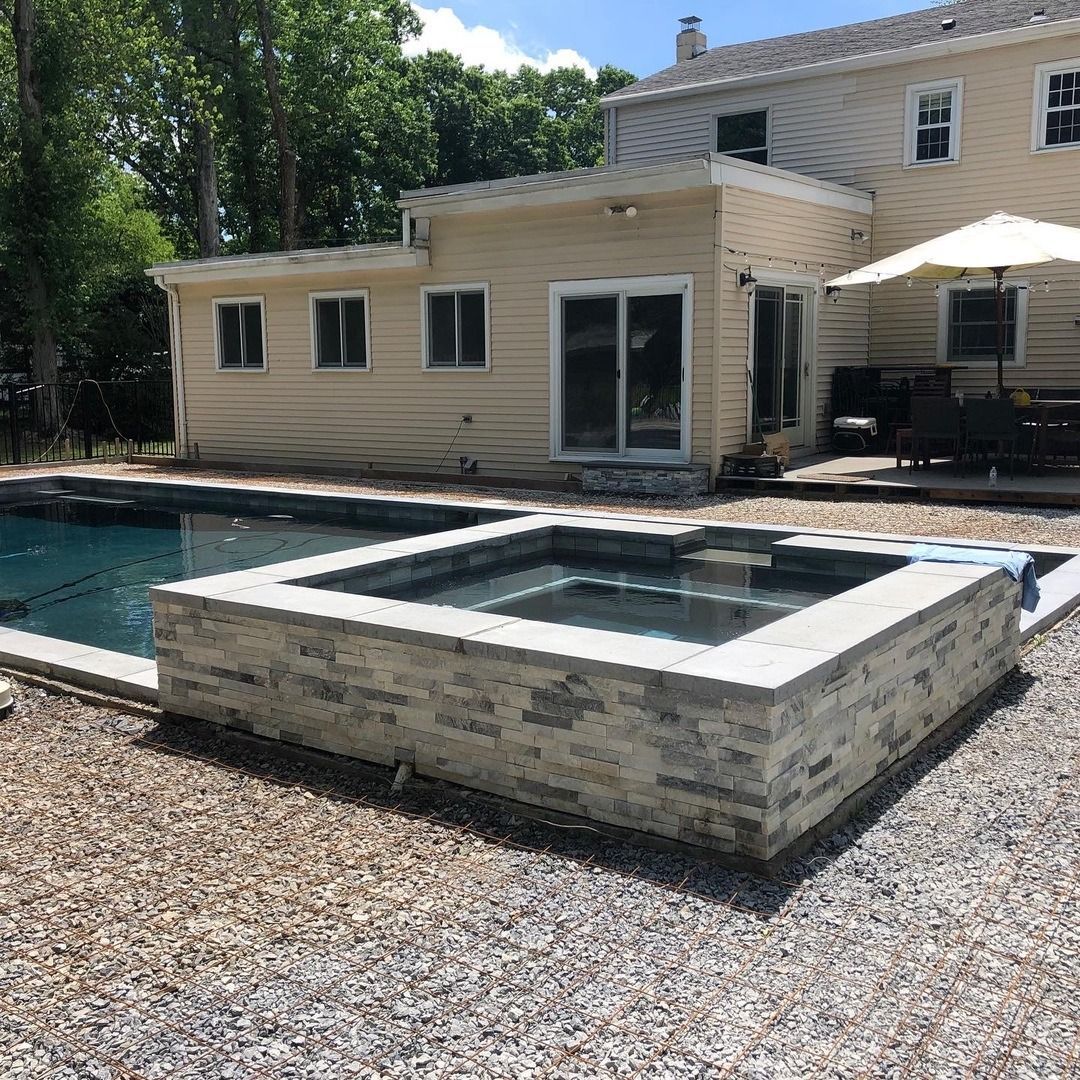 A large house with a swimming pool and a hot tub in front of it.