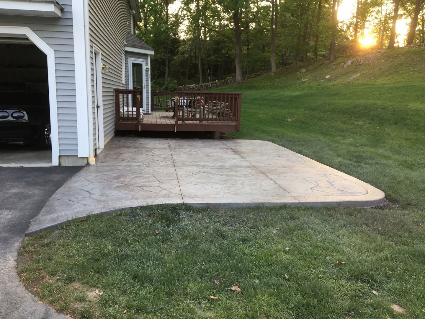 A concrete patio with a wooden deck in front of a house.