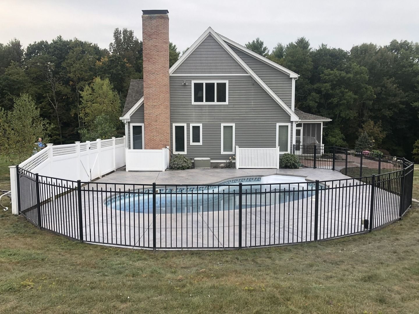 A large house with a swimming pool and a fence around it.