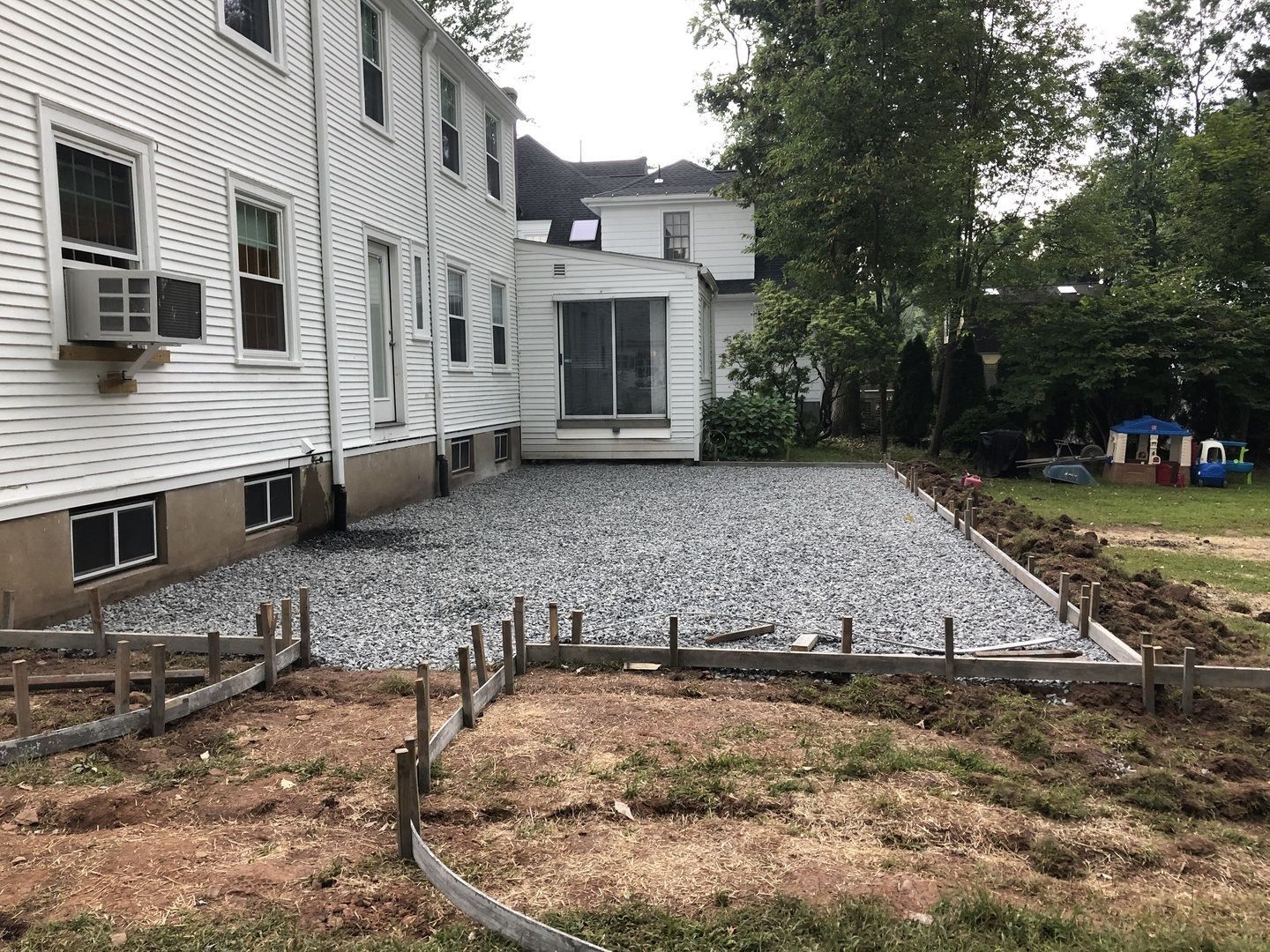 A white house with a gravel driveway in front of it.