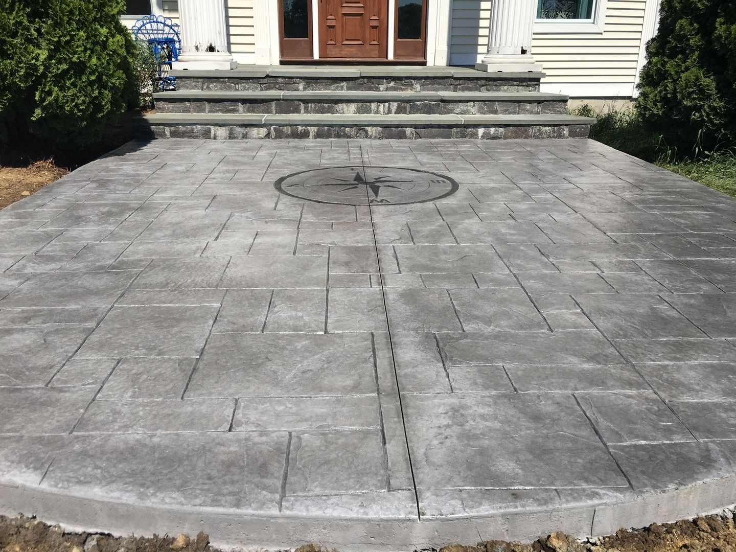 A circular concrete patio in front of a house.