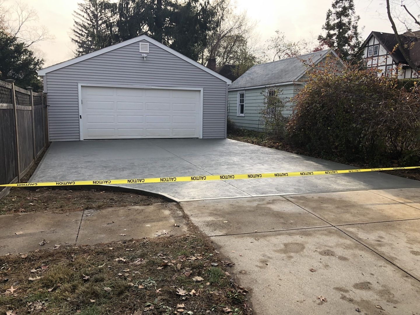 A concrete driveway leading to a garage with a yellow tape surrounding it.