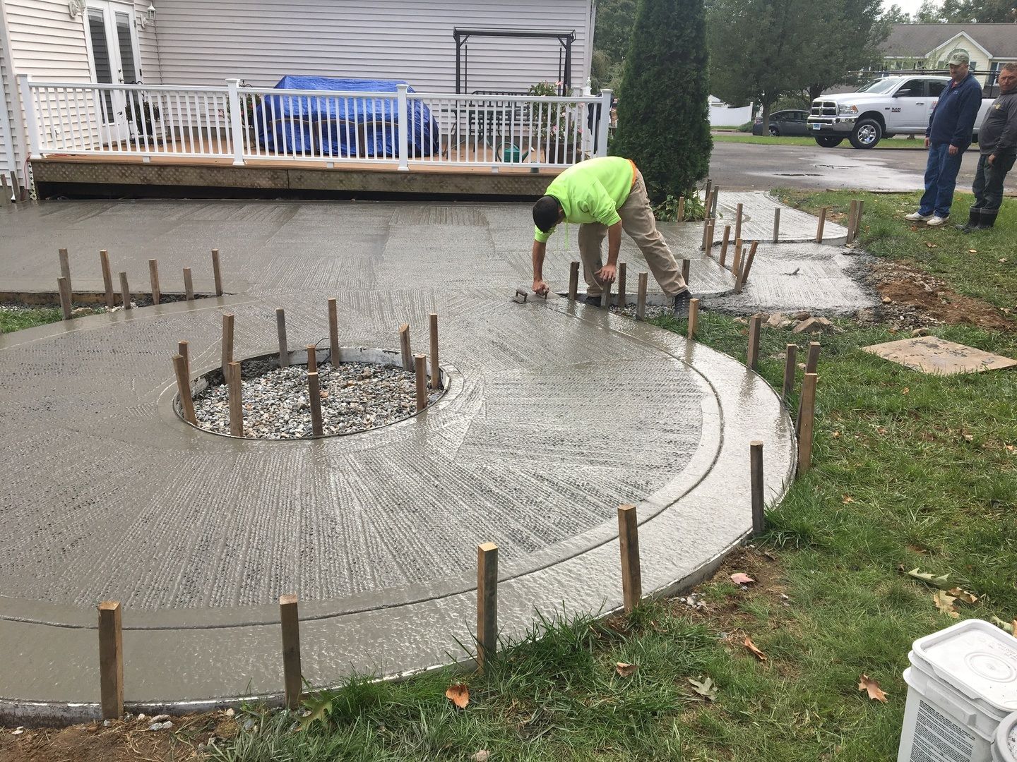 A man is working on a concrete patio in front of a house.