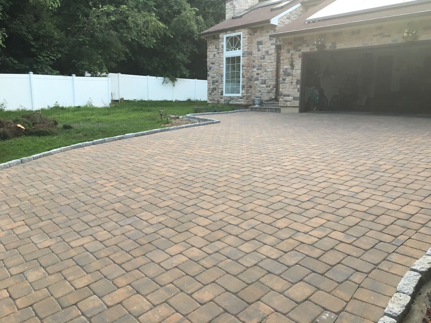 A brick driveway leading to a house with a garage.