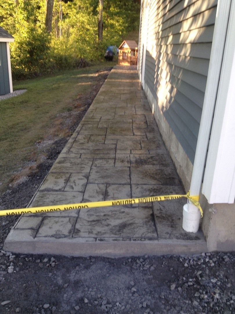 A concrete walkway leading to a house with a yellow caution tape.