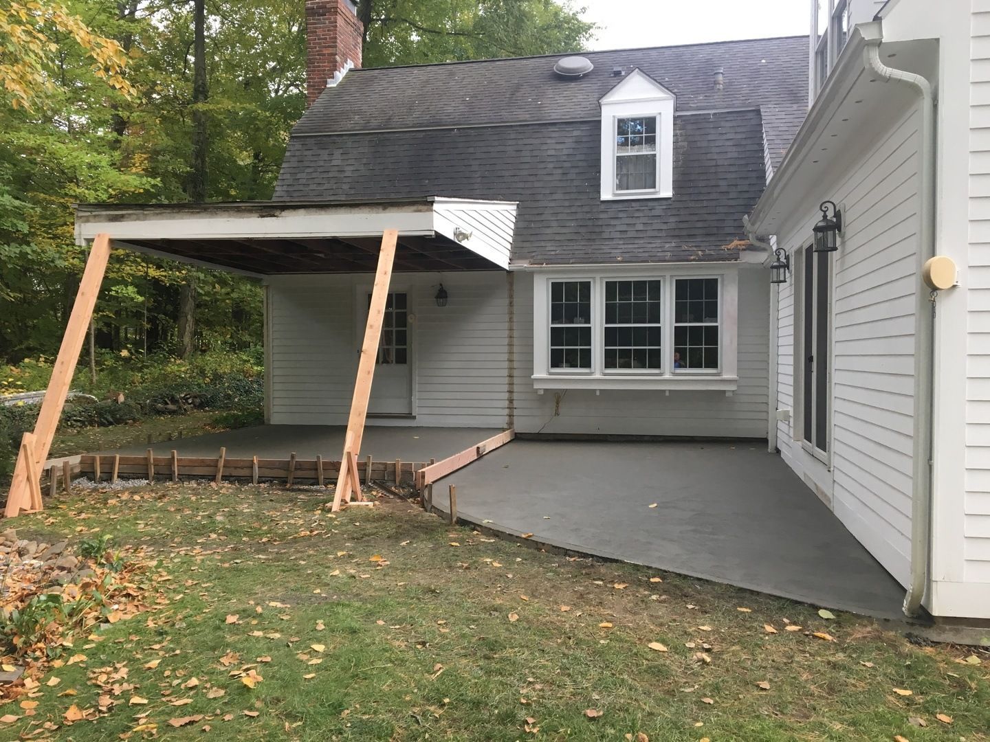 A white house with a covered patio in front of it.