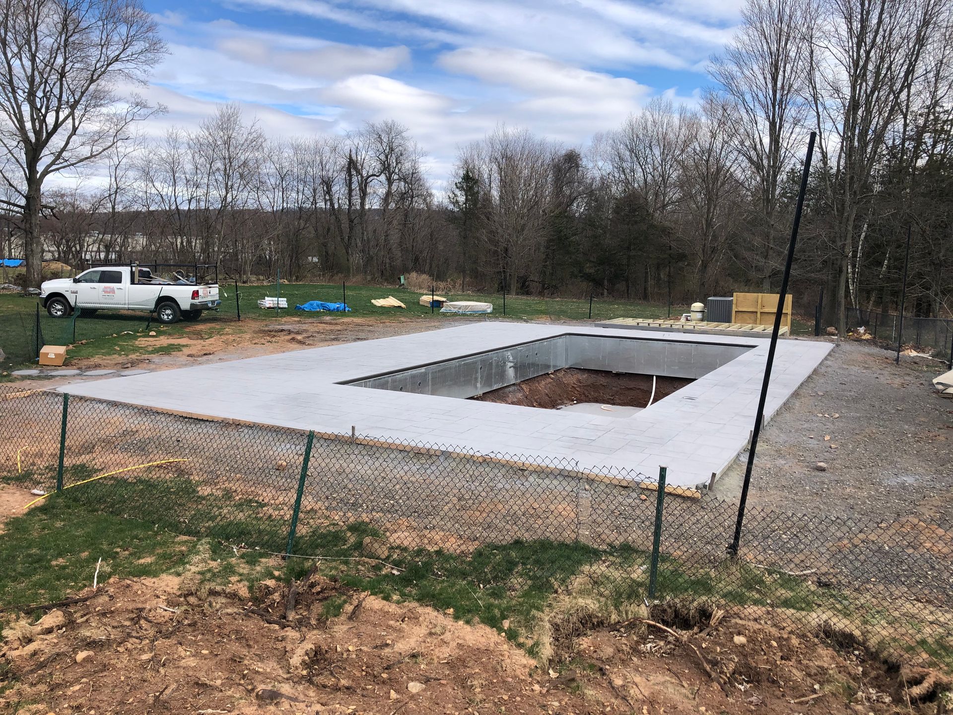 A truck is parked in front of a large swimming pool under construction.