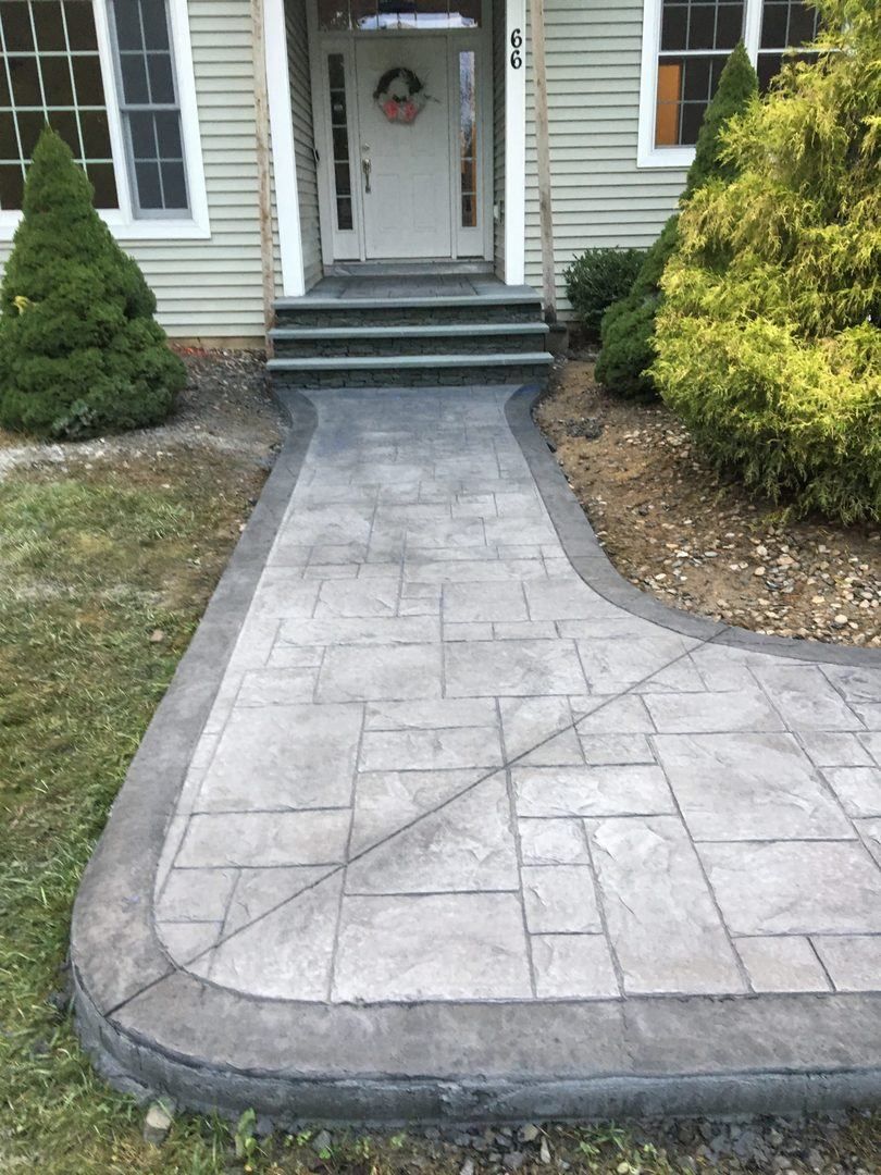 A concrete walkway leading to the front door of a house.