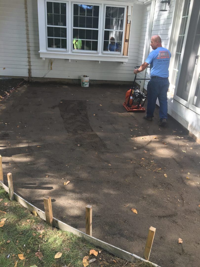 A man is standing in front of a house holding a tool.