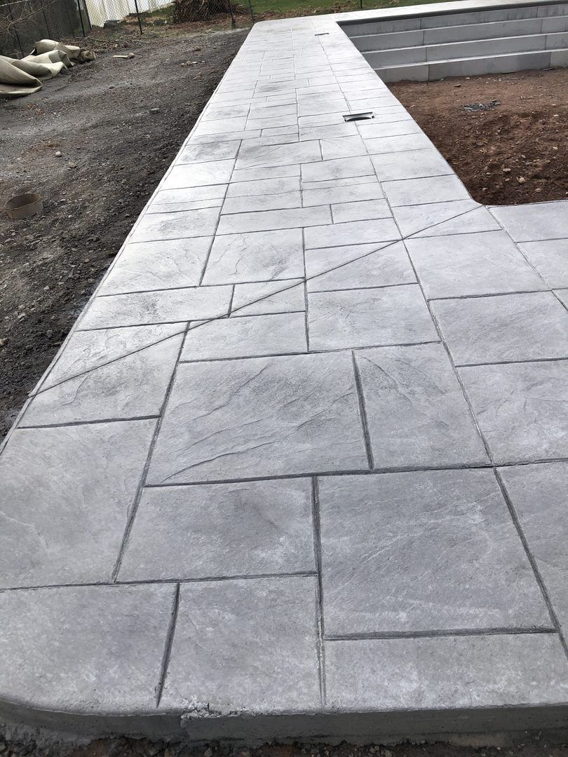 A concrete walkway is being built next to a pool.