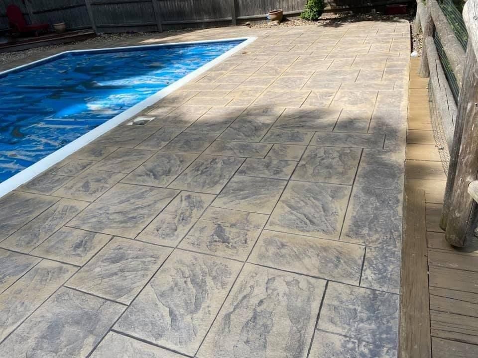 A swimming pool with a concrete deck in front of it.
