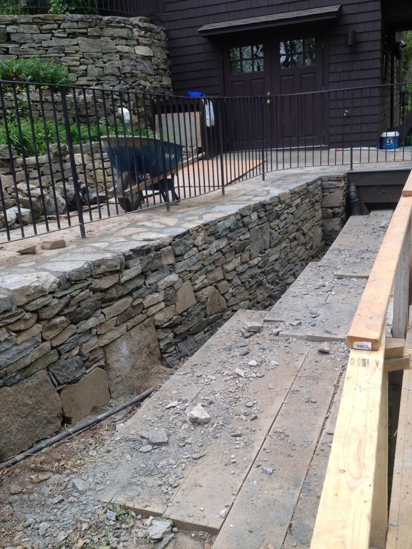A stone wall is being built in front of a house.