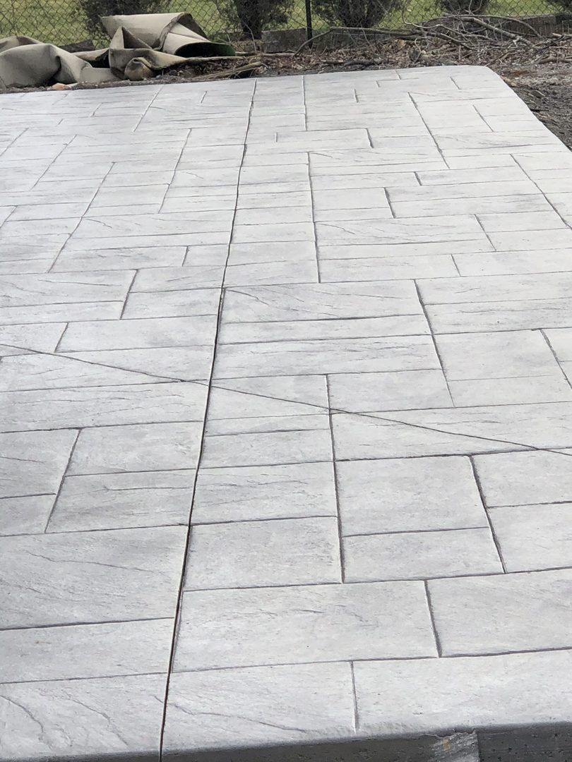 A close up of a concrete patio with rocks in the background
