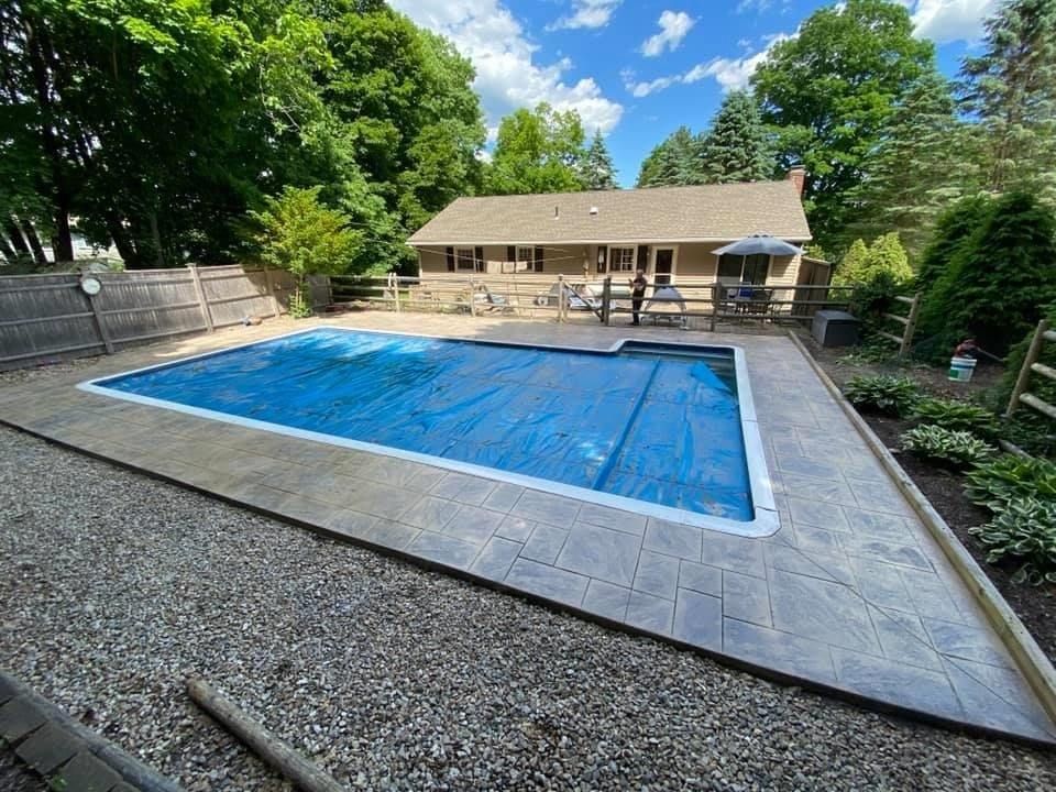 A large swimming pool is in the backyard of a house.