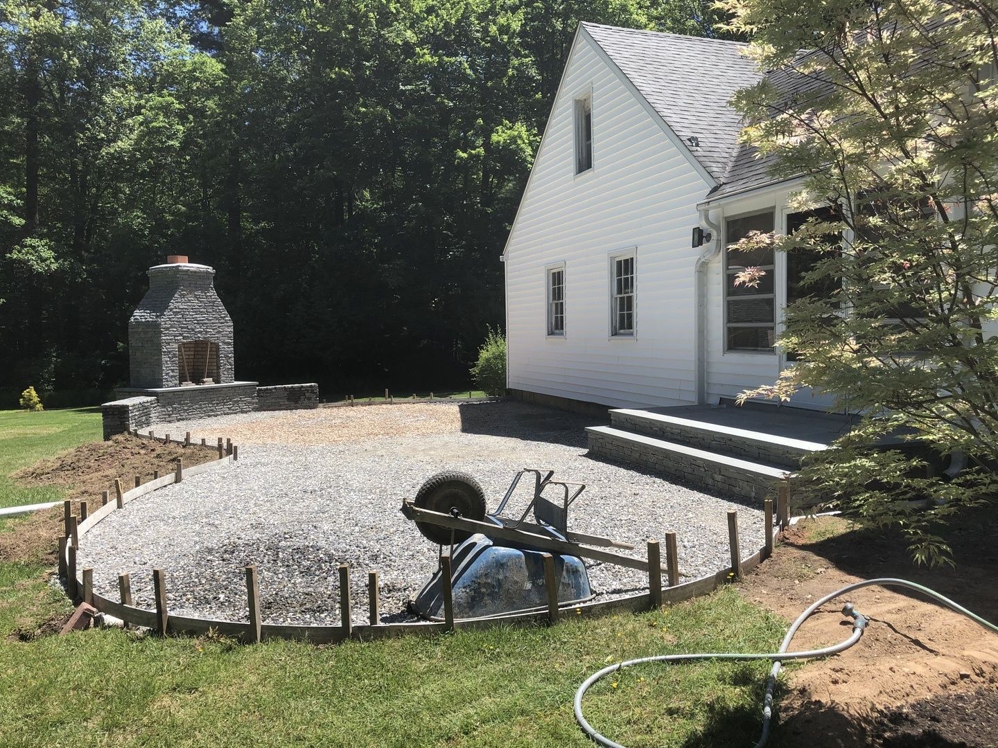 A white house with a fireplace in the backyard is being built.