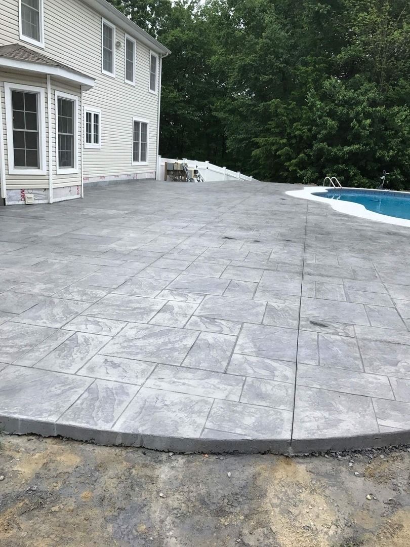 A patio with a pool in the backyard of a house.