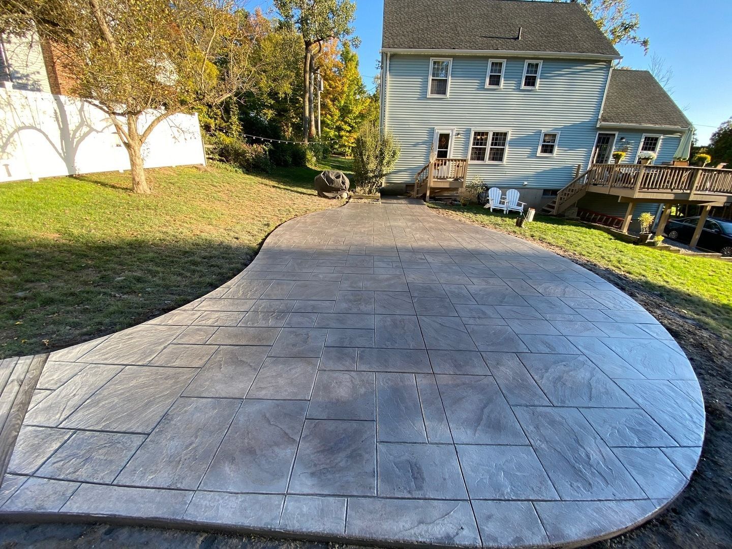 A concrete walkway leading to a house in a backyard.