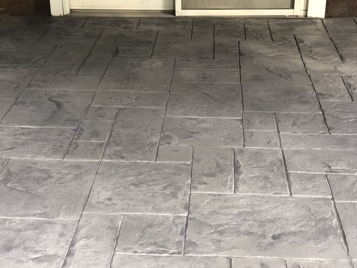 A close up of a concrete floor with a door in the background.