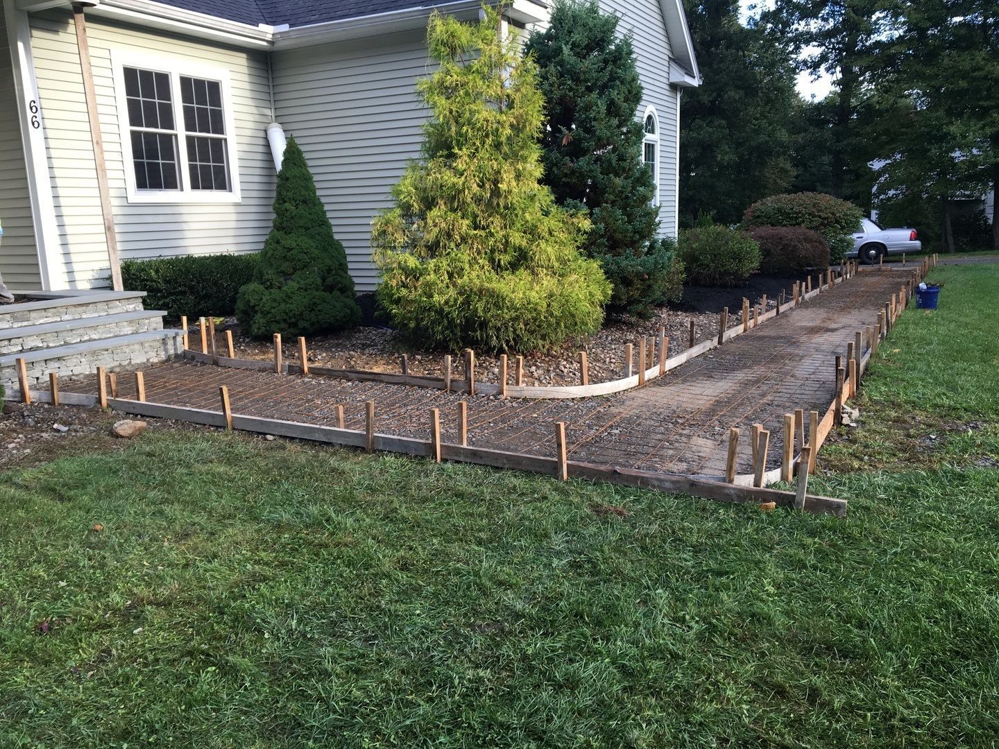 A concrete walkway is being built in front of a house.
